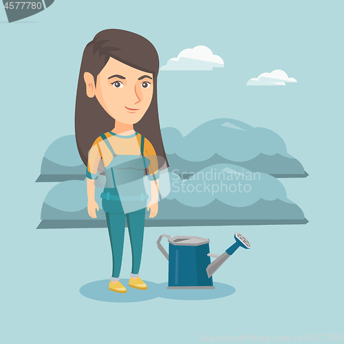 Image of Young farmer standing in a field with watering can