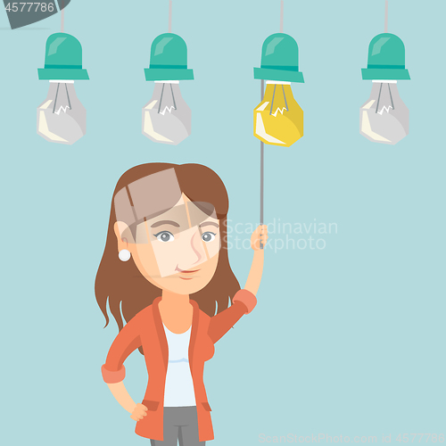 Image of Business woman switching on hanging idea bulb.
