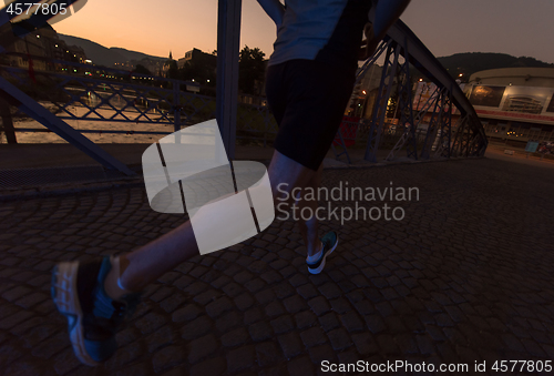 Image of man jogging across the bridge in the city