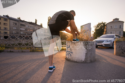 Image of man tying running shoes laces