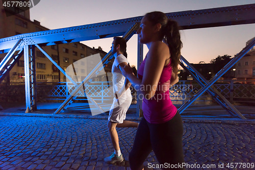 Image of couple jogging across the bridge in the city