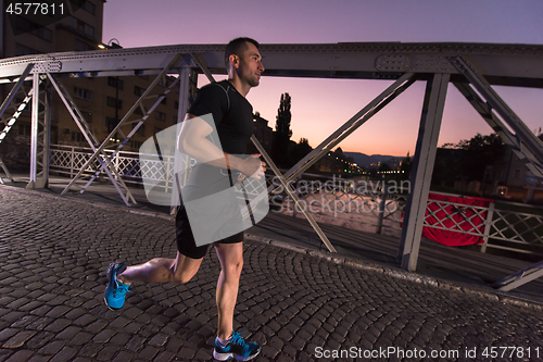 Image of man jogging across the bridge in the city