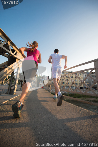 Image of young couple jogging across the bridge in the city