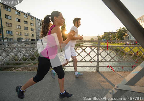 Image of young couple jogging across the bridge in the city