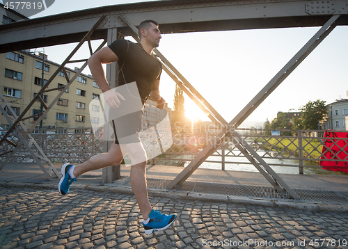 Image of man jogging across the bridge at sunny morning