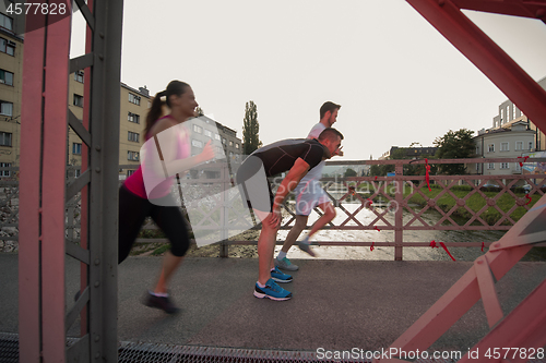 Image of group of young people jogging across the bridge