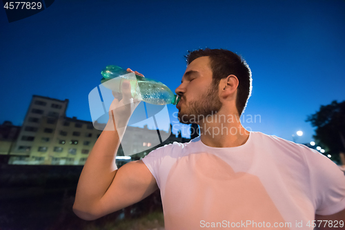 Image of man drinking water after running session