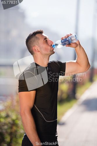 Image of man drinking water from a bottle after jogging
