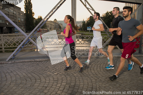 Image of group of young people jogging across the bridge