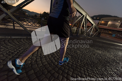 Image of man jogging across the bridge in the city