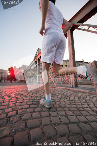 Image of man jogging across the bridge at sunny morning