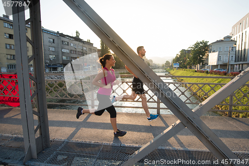 Image of young couple jogging across the bridge in the city