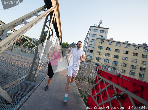 Image of young couple jogging across the bridge in the city