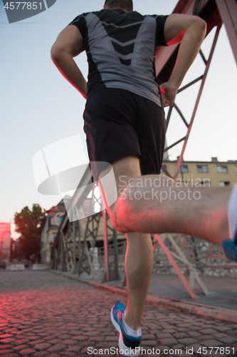 Image of man jogging across the bridge at sunny morning