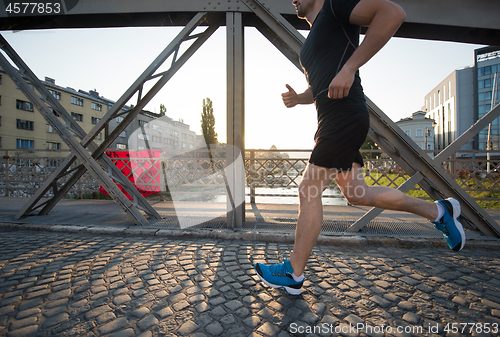 Image of man jogging across the bridge at sunny morning