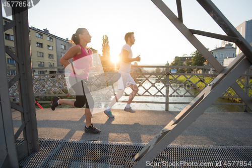 Image of young couple jogging across the bridge in the city