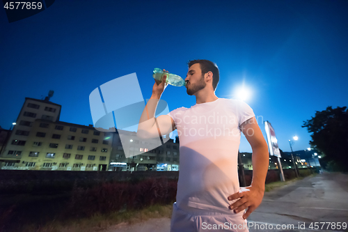 Image of man drinking water after running session