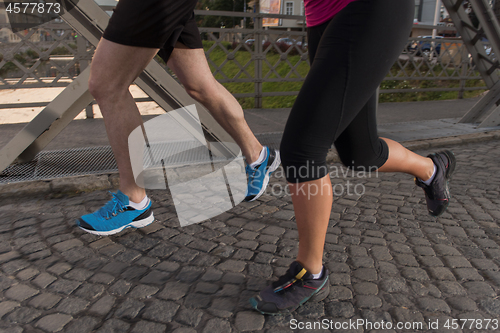 Image of young couple jogging across the bridge in the city