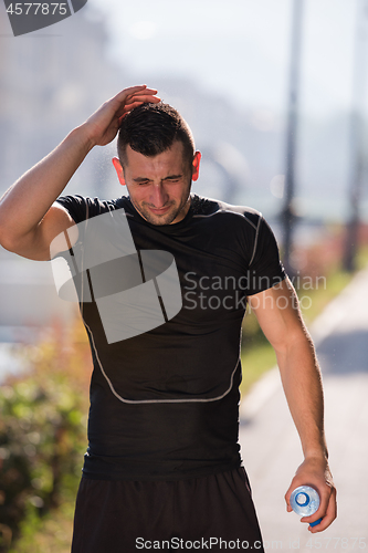 Image of man pouring water from bottle on his head