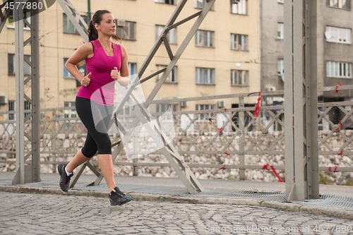 Image of woman jogging across the bridge at sunny morning