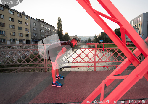 Image of man jogging across the bridge at sunny morning