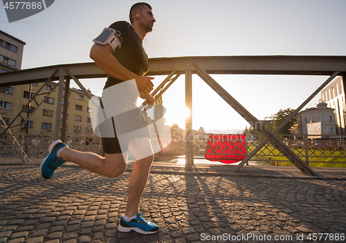 Image of man jogging across the bridge at sunny morning