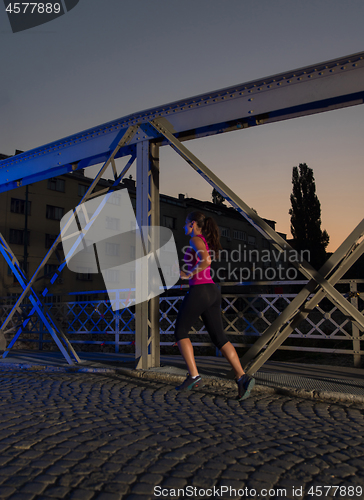 Image of woman jogging across the bridge in the city