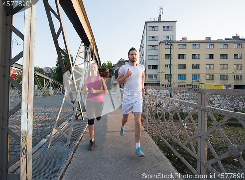 Image of young couple jogging across the bridge in the city