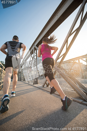 Image of young couple jogging across the bridge in the city