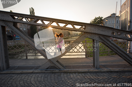 Image of woman jogging across the bridge at sunny morning