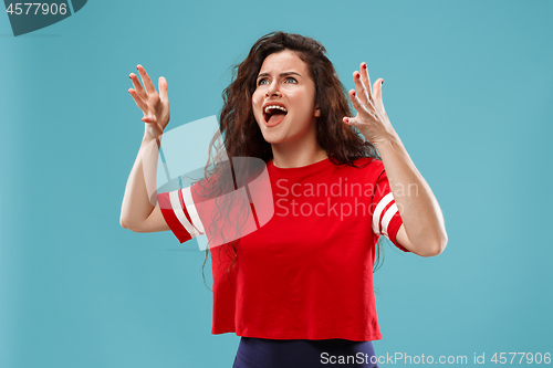 Image of The young emotional angry woman screaming on blue studio background