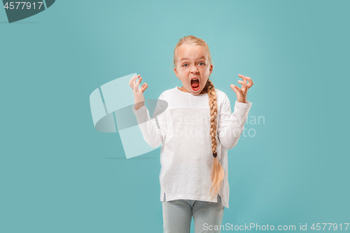 Image of Portrait of angry teen girl on a blue studio background