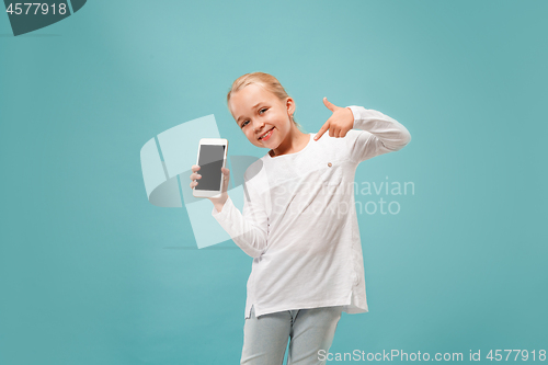 Image of The happy teen girl standing and smiling against blue background.