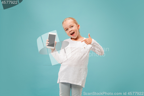 Image of The happy teen girl standing and smiling against blue background.