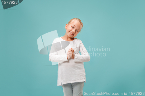 Image of The happy teen girl standing and smiling against blue background.