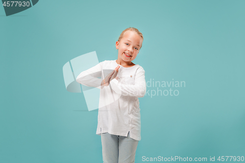 Image of The happy teen girl standing and smiling against blue background.