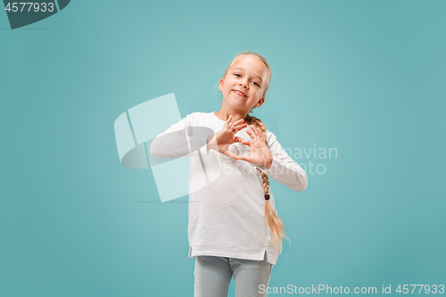 Image of Beautiful smiling teen girl makes the shape of a heart with her hands on the blue background.