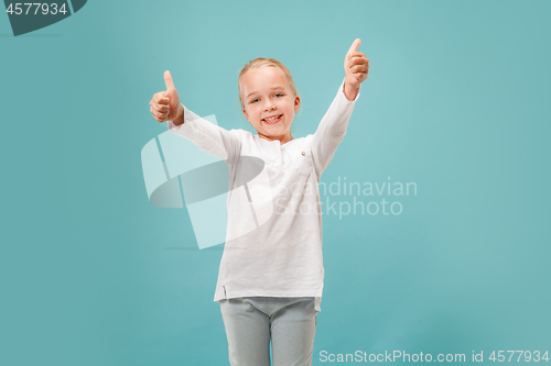 Image of The happy teen girl standing and smiling against blue background.