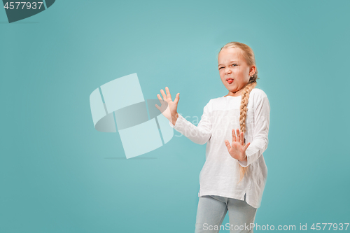 Image of Doubtful pensive teen girl rejecting something against blue background