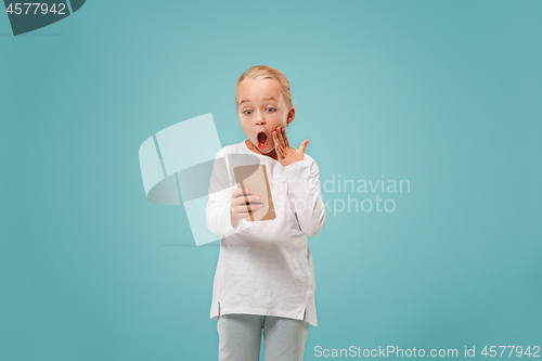 Image of The happy teen girl standing and smiling against blue background.