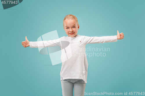 Image of The happy teen girl standing and smiling against blue background.