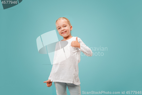 Image of The happy teen girl standing and smiling against blue background.