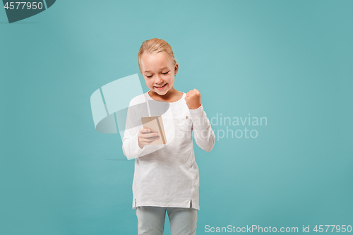 Image of The happy teen girl standing and smiling against blue background.