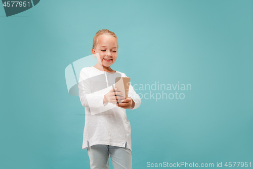 Image of The happy teen girl standing and smiling against blue background.