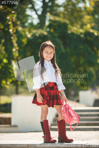 Image of Beautiful little girl with backpack walking in the park ready back to school