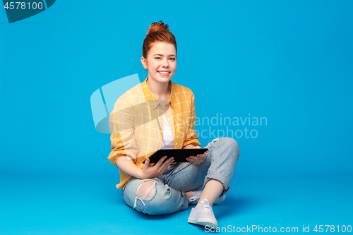 Image of red haired teenage girl using tablet computer