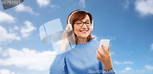 Image of senior woman in headphones listening music on cell