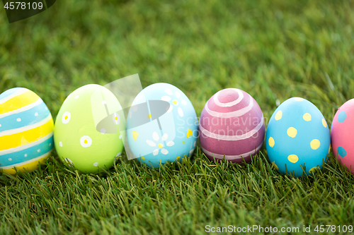 Image of row of colored easter eggs on artificial grass