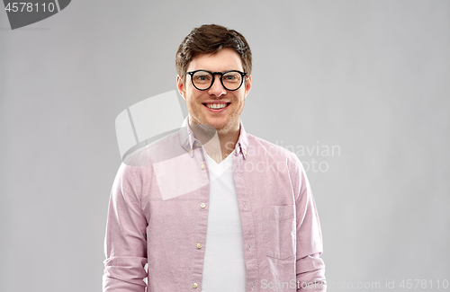 Image of smiling young man in glasses over grey background