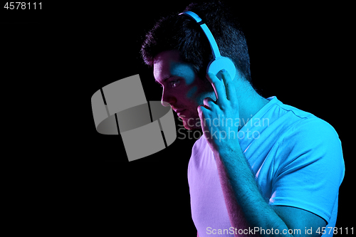 Image of man in headphones over neon lights of night club